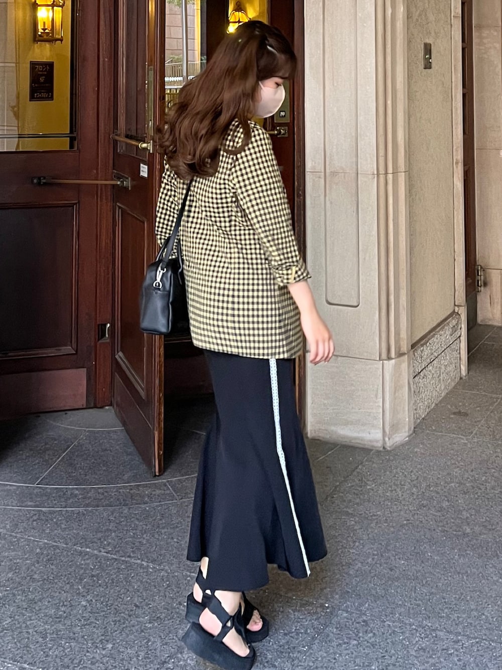 イエロー系のテーラードジャケット、ブラック系のキャミソール、ブラック系のショルダーバッグを着用したレディースの夏コーディネートの2枚目の写真