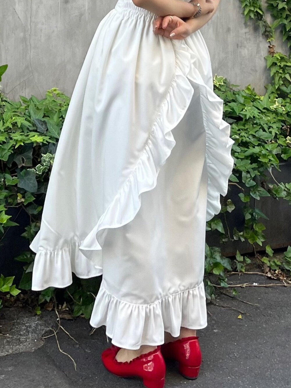 ホワイト系のスカート、レッド系のパンプス、ホワイト系のポロシャツを着用したレディースの春コーディネートの2枚目の写真