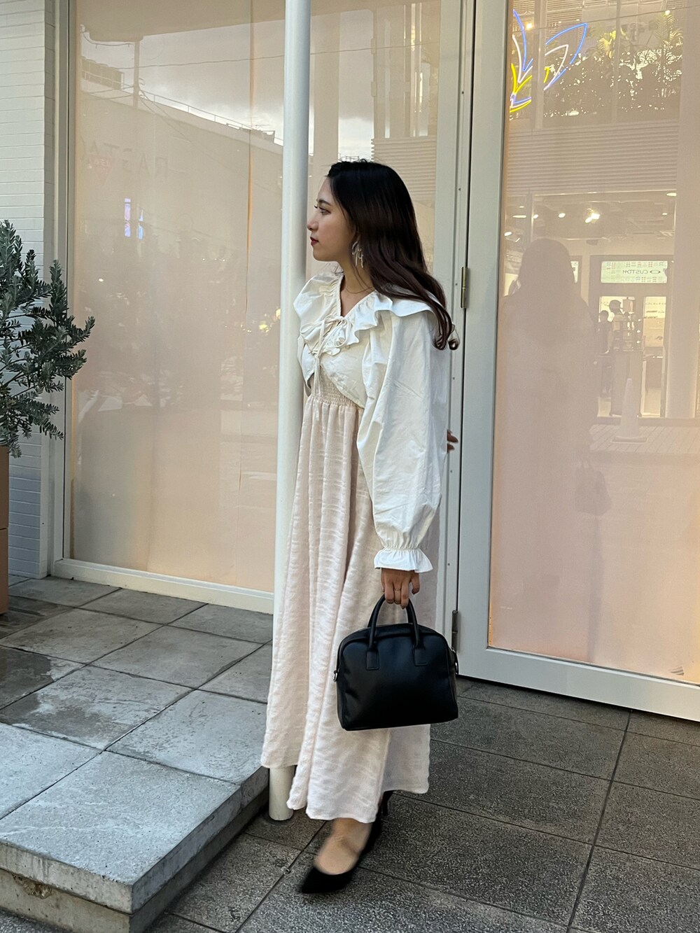 ブラック系のショルダーバッグ、ピンク系のワンピース/ドレス、ホワイト系のカーディガン/ボレロを着用したレディースの春コーディネートの2枚目の写真