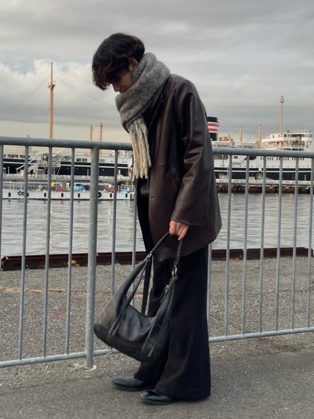 ブラック系のハンドバッグ、ブラック系のその他パンツ、ブラック系のブーツを着用したメンズの冬コーディネートの3枚目の写真