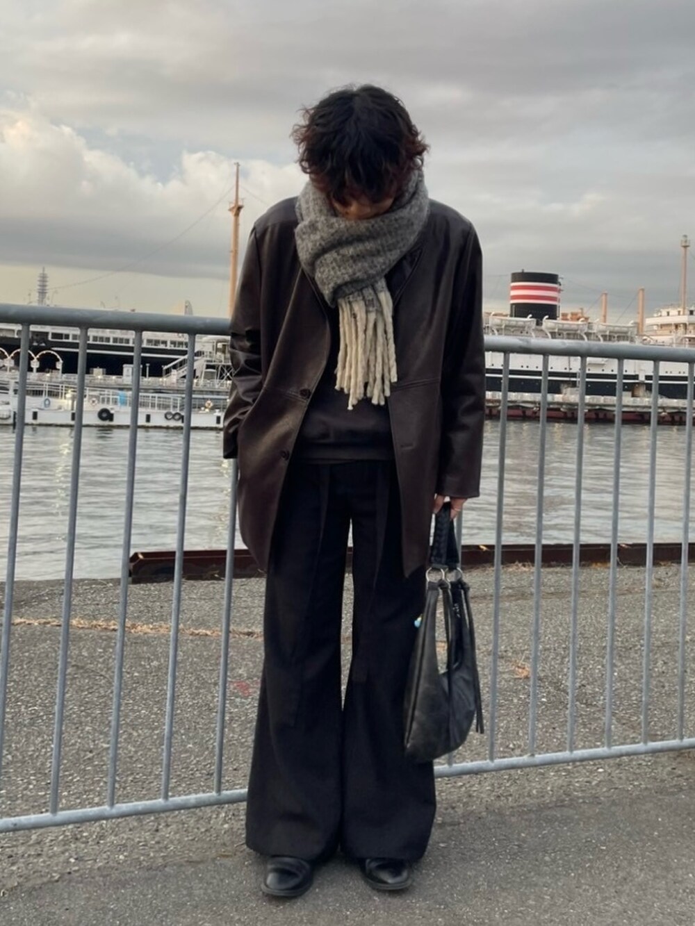 ブラック系のハンドバッグ、ブラック系のその他パンツ、ブラック系のブーツを着用したメンズの冬コーディネートの2枚目の写真
