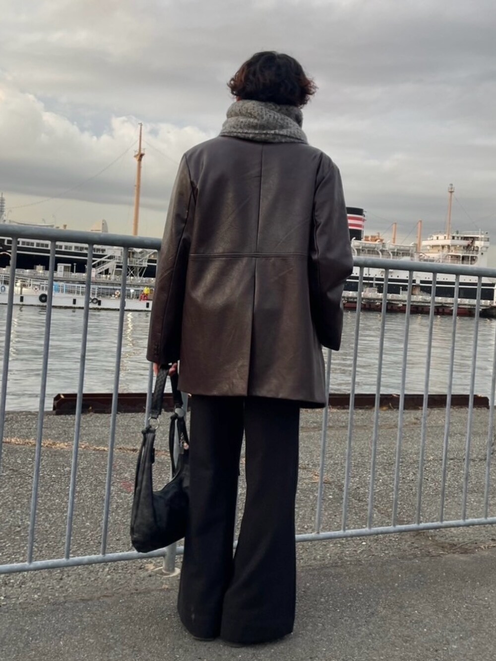ブラック系のハンドバッグ、ブラック系のその他パンツ、ブラック系のブーツを着用したメンズの冬コーディネートの4枚目の写真