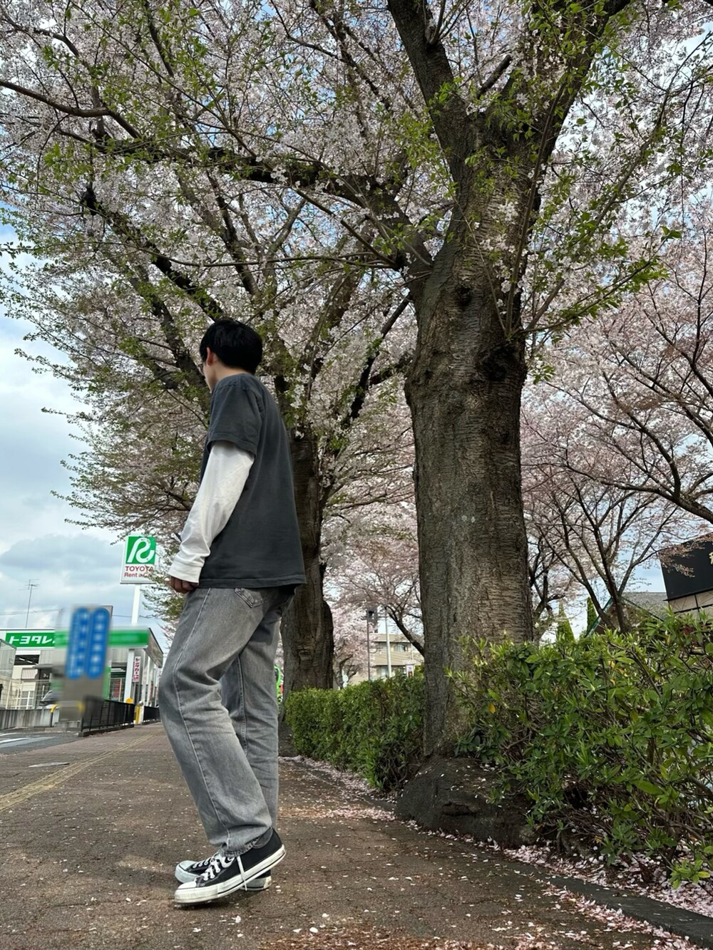 グレー系のデニムパンツ、ブラック系のスニーカー、ブラック系のTシャツ/カットソーを着用したメンズの春コーディネートの2枚目の写真