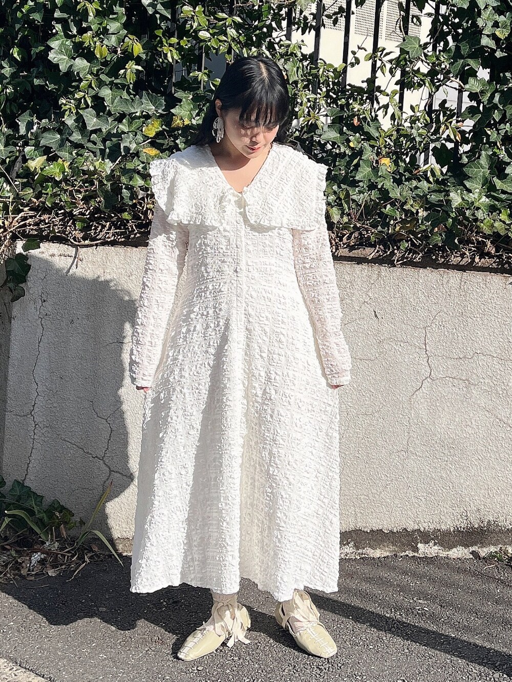 ホワイト系のワンピース、グリーン系のパンプス、シルバー系のイヤリングを着用したレディースの冬コーディネートの2枚目の写真