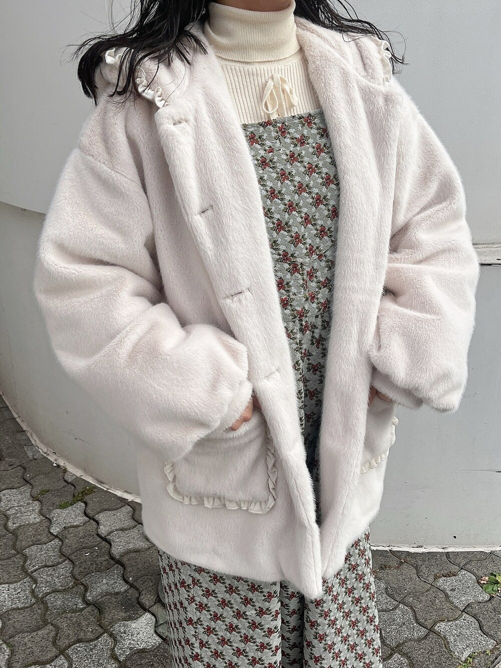 ホワイト系のニット/セーター、ホワイト系のダウンジャケット/コート、グリーン系のジャンパースカートを着用したレディースの冬コーディネートの7枚目の写真