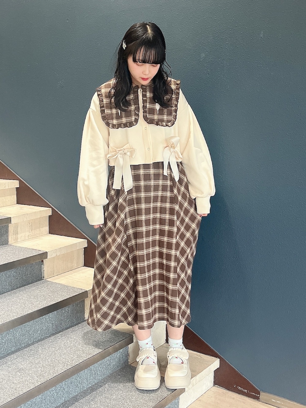 ブラウン系のワンピース、ホワイト系のカーディガン/ボレロ、ホワイト系のスニーカーを着用したレディースの冬コーディネートの2枚目の写真