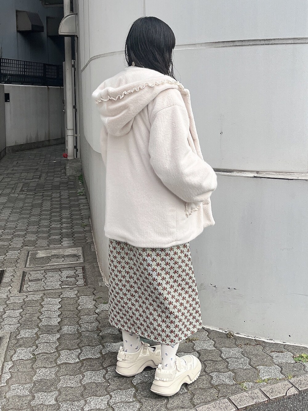 ホワイト系のニット/セーター、ホワイト系のダウンジャケット/コート、グリーン系のジャンパースカートを着用したレディースの冬コーディネートの4枚目の写真