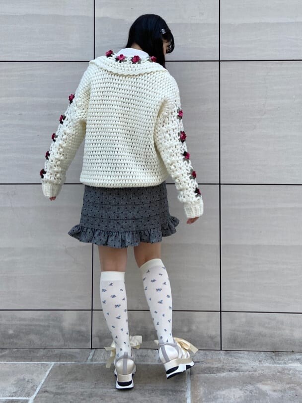 ホワイト系のスニーカー、ホワイト系のカーディガン/ボレロ、グレー系のスカートを着用したレディースの冬コーディネートの2枚目の写真