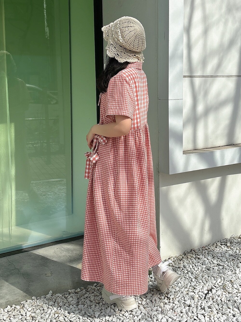 レッド系のワンピース、ホワイト系のスニーカー、ホワイト系のハットを着用したレディースの春コーディネートの4枚目の写真