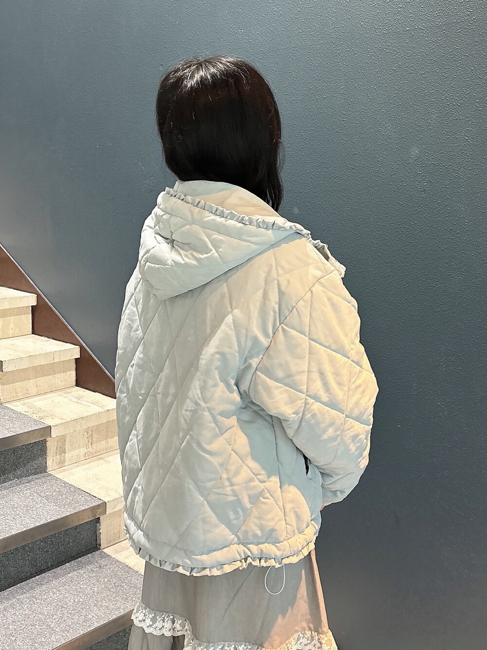 ブルー系のダウンジャケット/コート、ホワイト系のニット/セーター、グレー系のスカートを着用したレディースの秋コーディネートの7枚目の写真