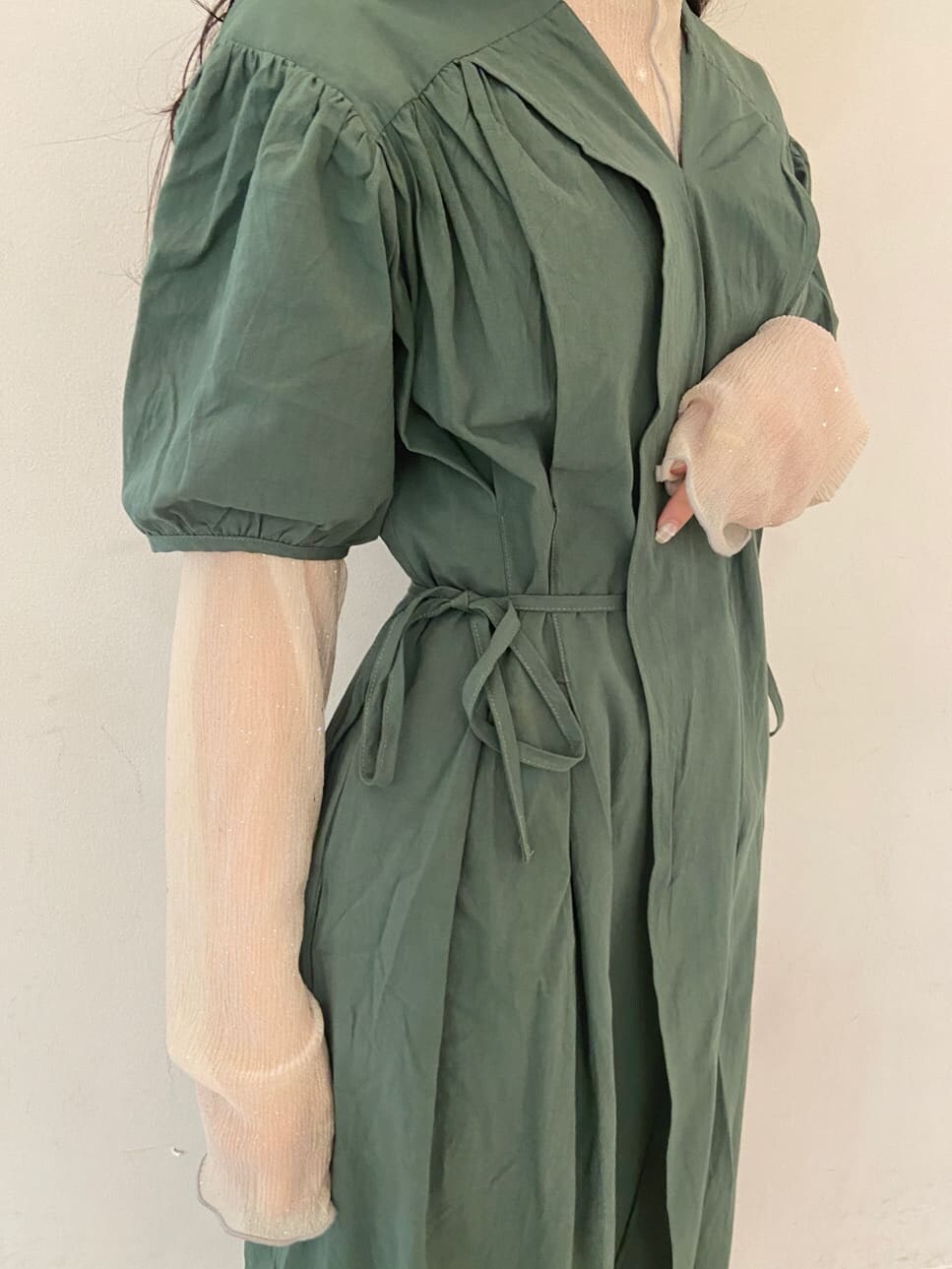 ベージュ系のパンプス、グリーン系のワンピース、ホワイト系のチュニックを着用したレディースの夏コーディネートの5枚目の写真