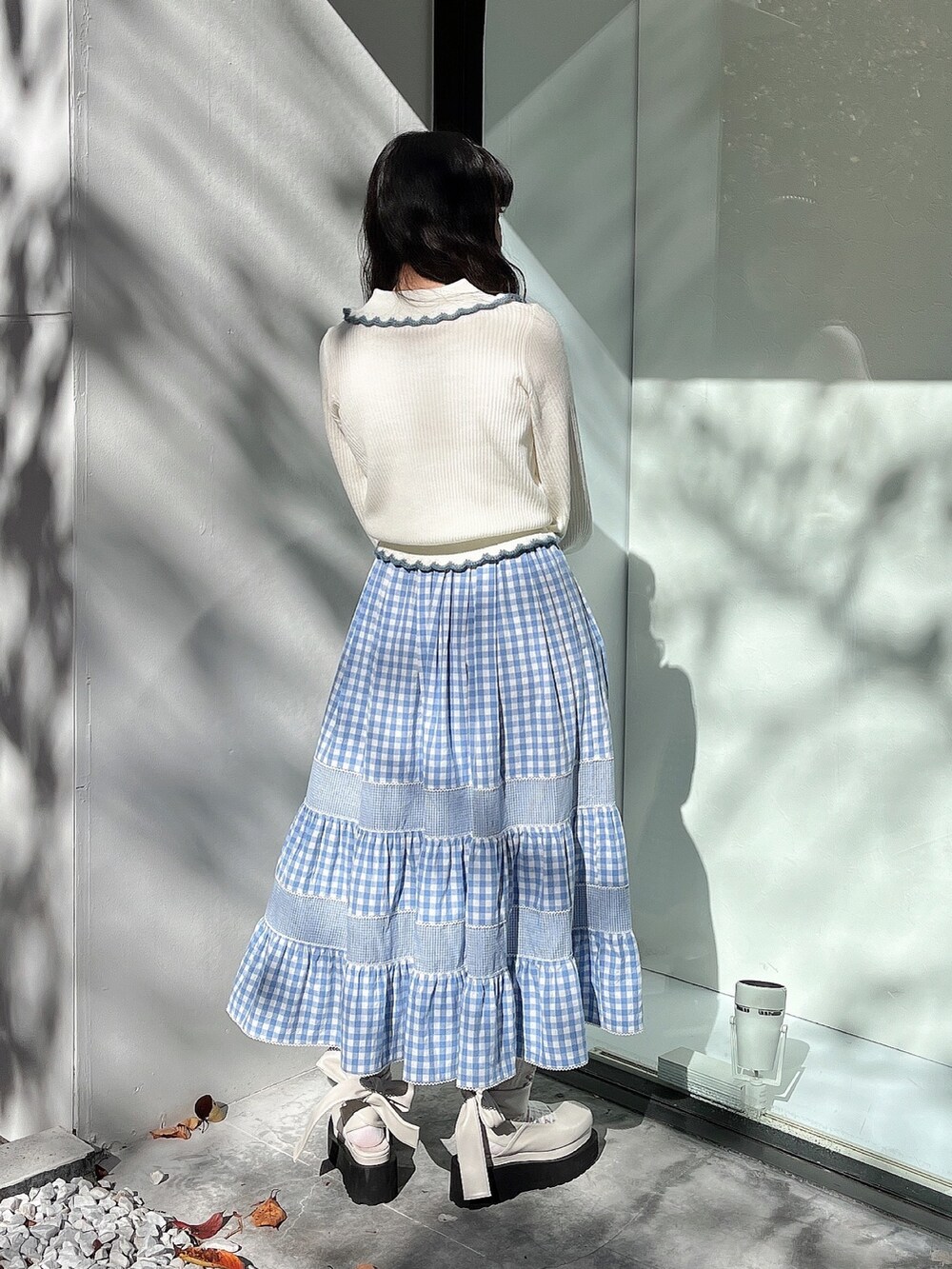 ホワイト系のニット/セーター、ブルー系のスカート、ホワイト系のパンプスを着用したレディースの秋コーディネートの3枚目の写真