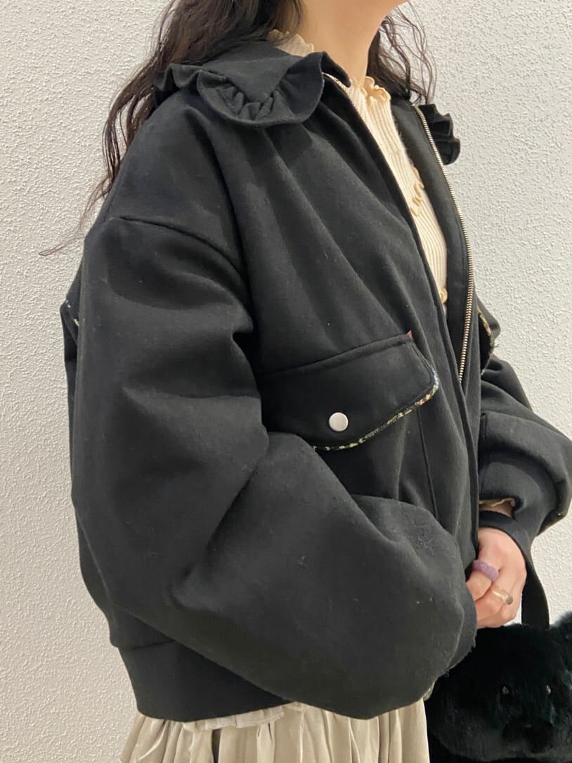 ブラック系のハンドバッグ、ブラック系のブーツ、ベージュ系のスカートを着用したレディースの冬コーディネートの8枚目の写真