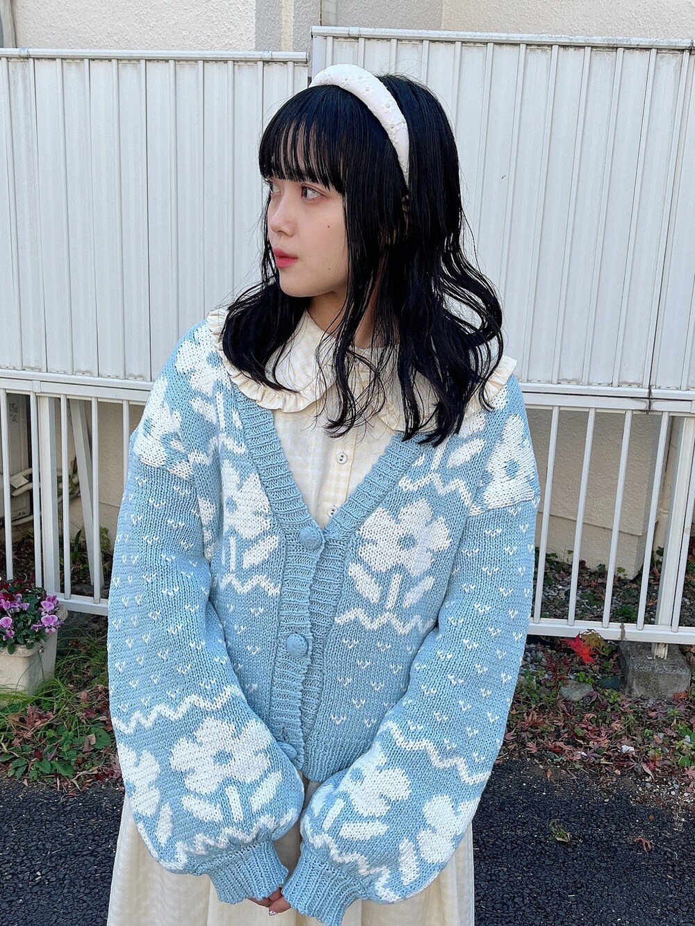 イエロー系のワンピース、ブルー系のカーディガン/ボレロ、ホワイト系のスニーカーを着用したレディースの冬コーディネートの6枚目の写真