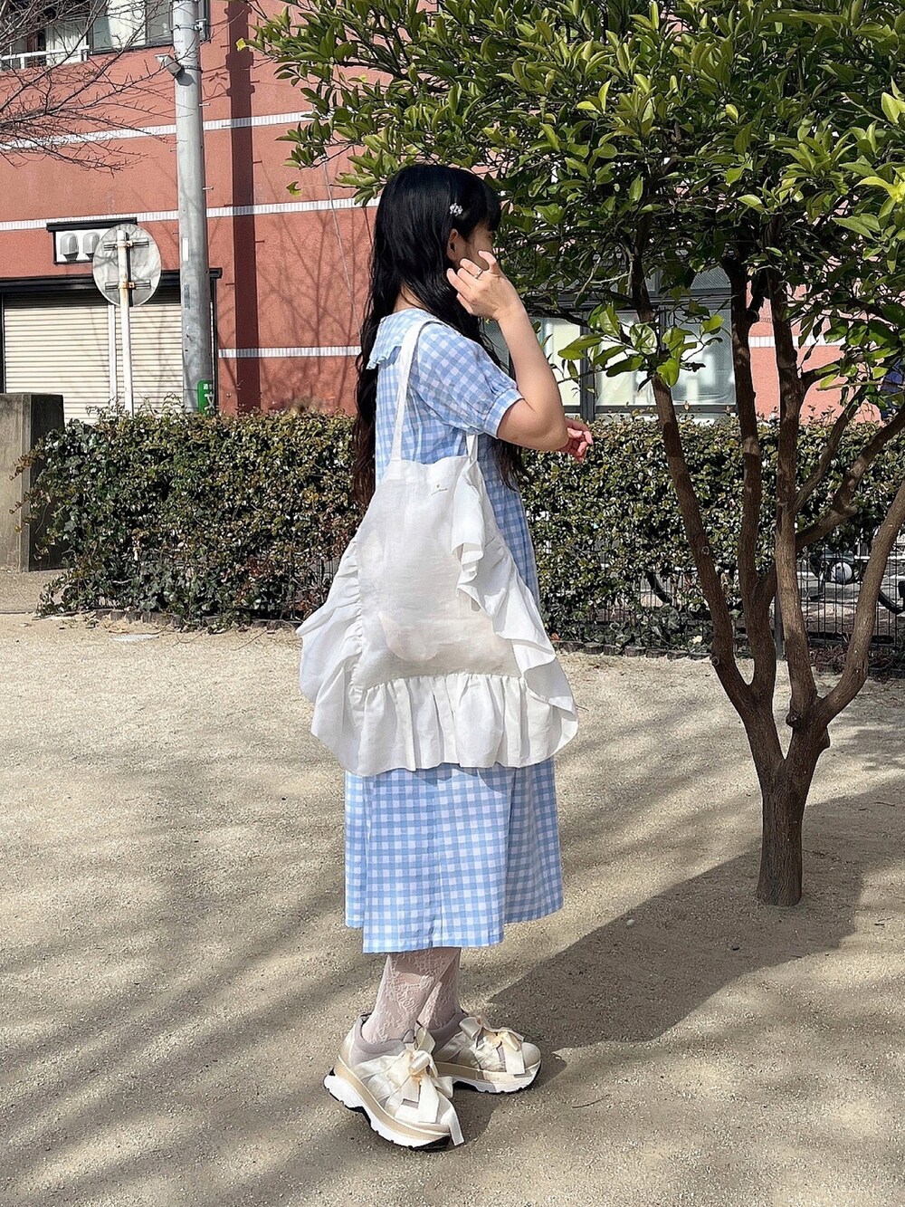 ホワイト系のトートバッグ、ブルー系のワンピース、ホワイト系のスニーカーを着用したレディースの冬コーディネートの3枚目の写真