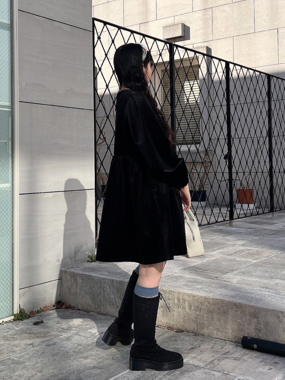 ブラック系のワンピース、ホワイト系のボストンバッグ、ブラック系のブーツを着用したレディースの冬コーディネートの3枚目の写真