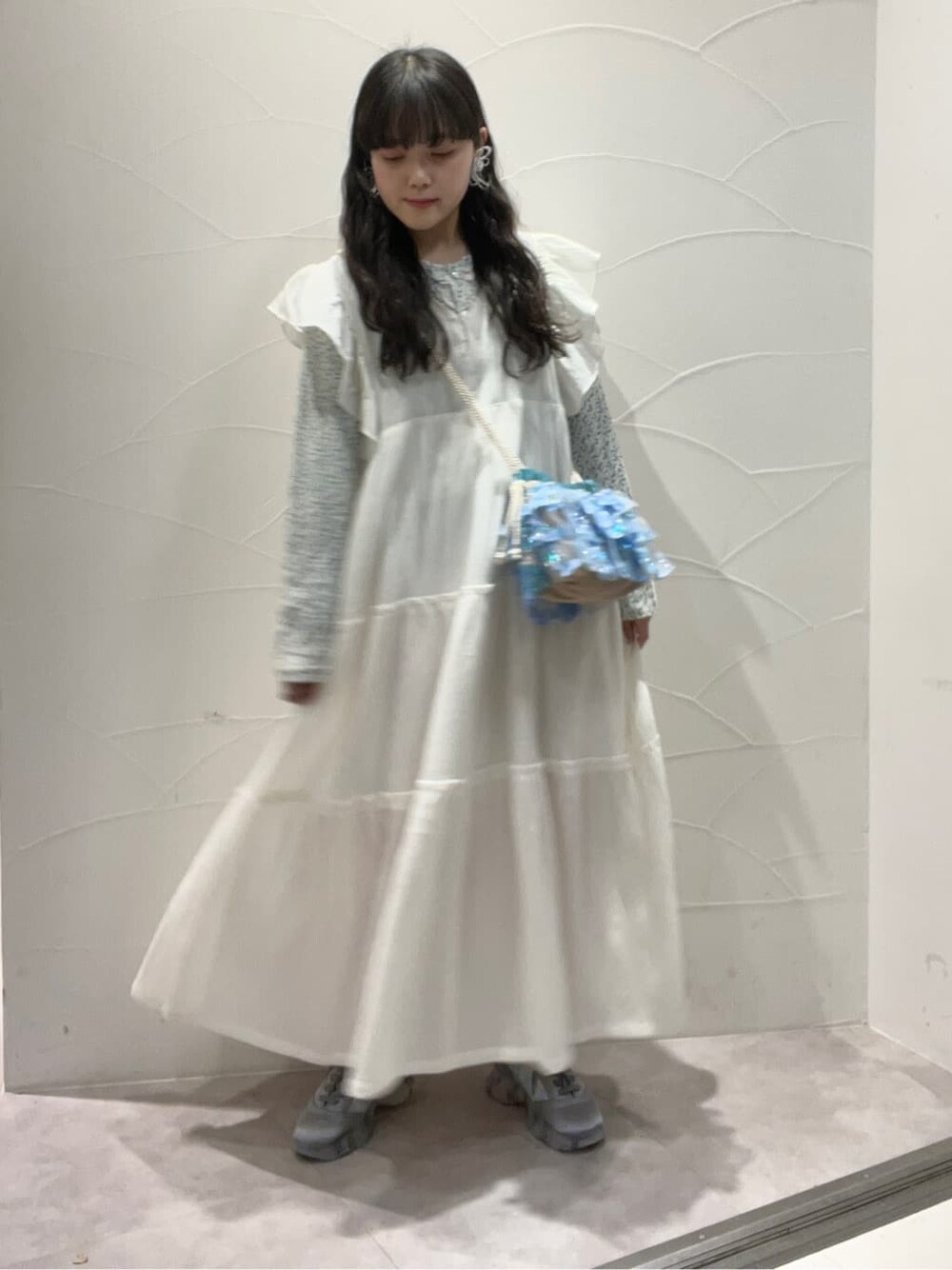 ホワイト系のワンピース、ブルー系のスニーカー、ブルー系のハンドバッグを着用したレディースの冬コーディネートの2枚目の写真