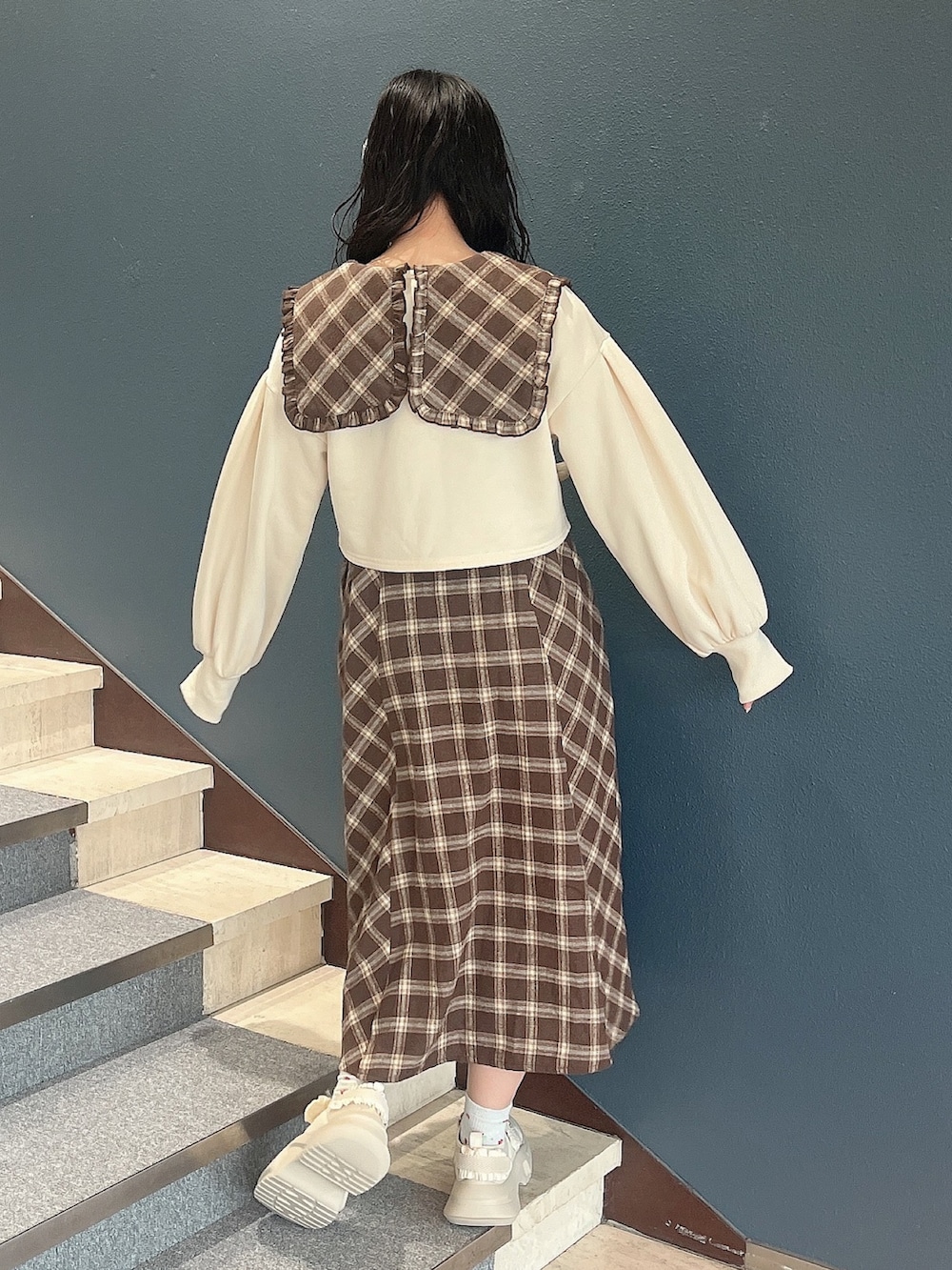 ブラウン系のワンピース、ホワイト系のカーディガン/ボレロ、ホワイト系のスニーカーを着用したレディースの冬コーディネートの3枚目の写真