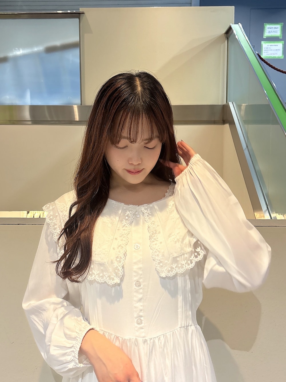 グリーン系のハンドバッグ、ホワイト系のスニーカー、ホワイト系のワンピースを着用したレディースの冬コーディネートの6枚目の写真