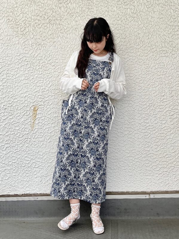 ベージュ系のサンダル、ブルー系のジャンパースカート、ホワイト系のカーディガン/ボレロを着用したレディースの夏コーディネートの2枚目の写真