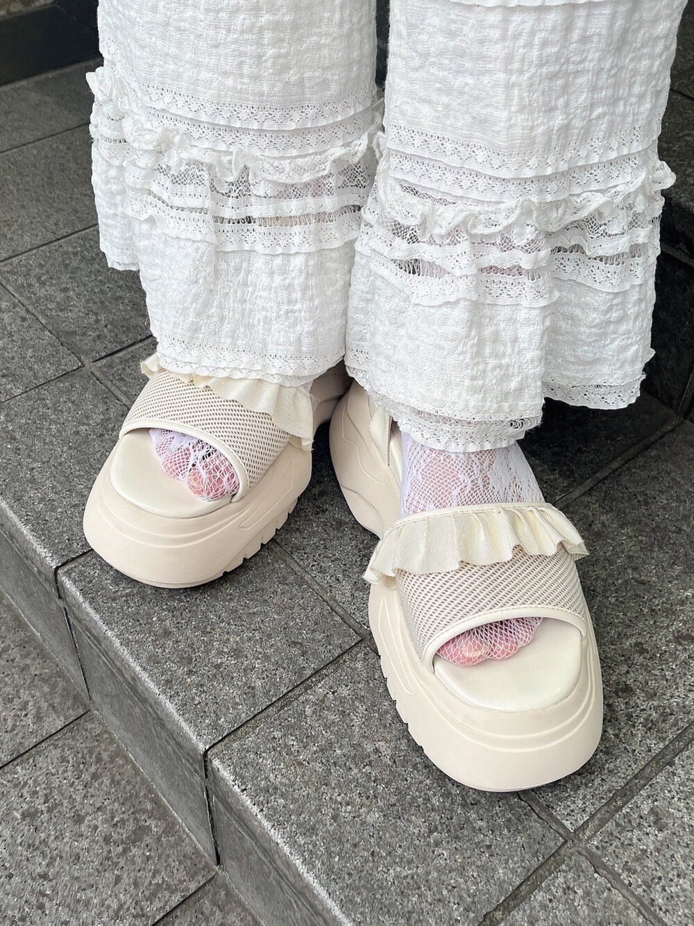 ホワイト系のTシャツ/カットソー、ホワイト系のスラックス、ホワイト系のサンダルを着用したレディースの夏コーディネートの6枚目の写真