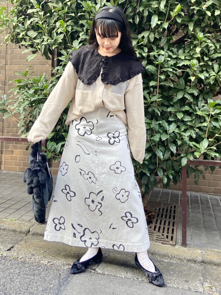 ブラック系のハンドバッグ、ホワイト系のカーディガン/ボレロ、ホワイト系のスカートを着用したレディースの秋コーディネートの2枚目の写真