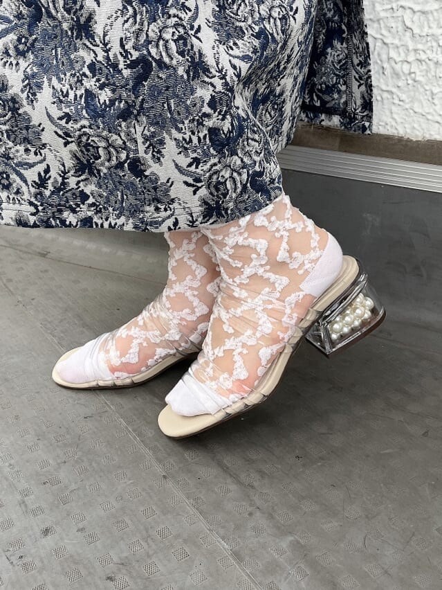 ベージュ系のサンダル、ブルー系のジャンパースカート、ホワイト系のカーディガン/ボレロを着用したレディースの夏コーディネートの4枚目の写真