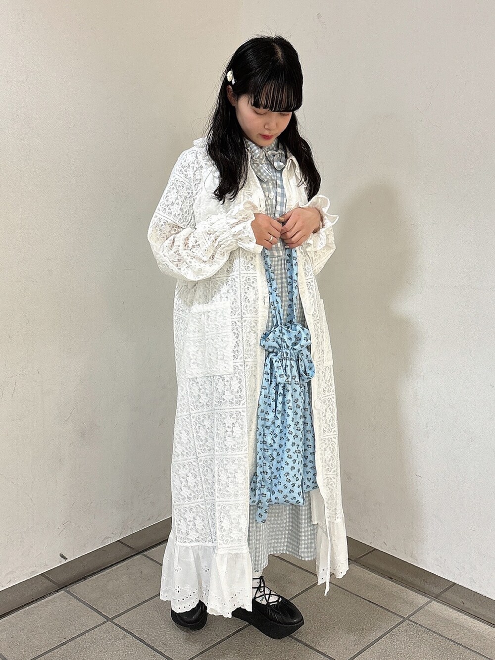 ブルー系のワンピース、ホワイト系のトレンチコート、ブラック系のバレエシューズを着用したレディースの春コーディネートの2枚目の写真