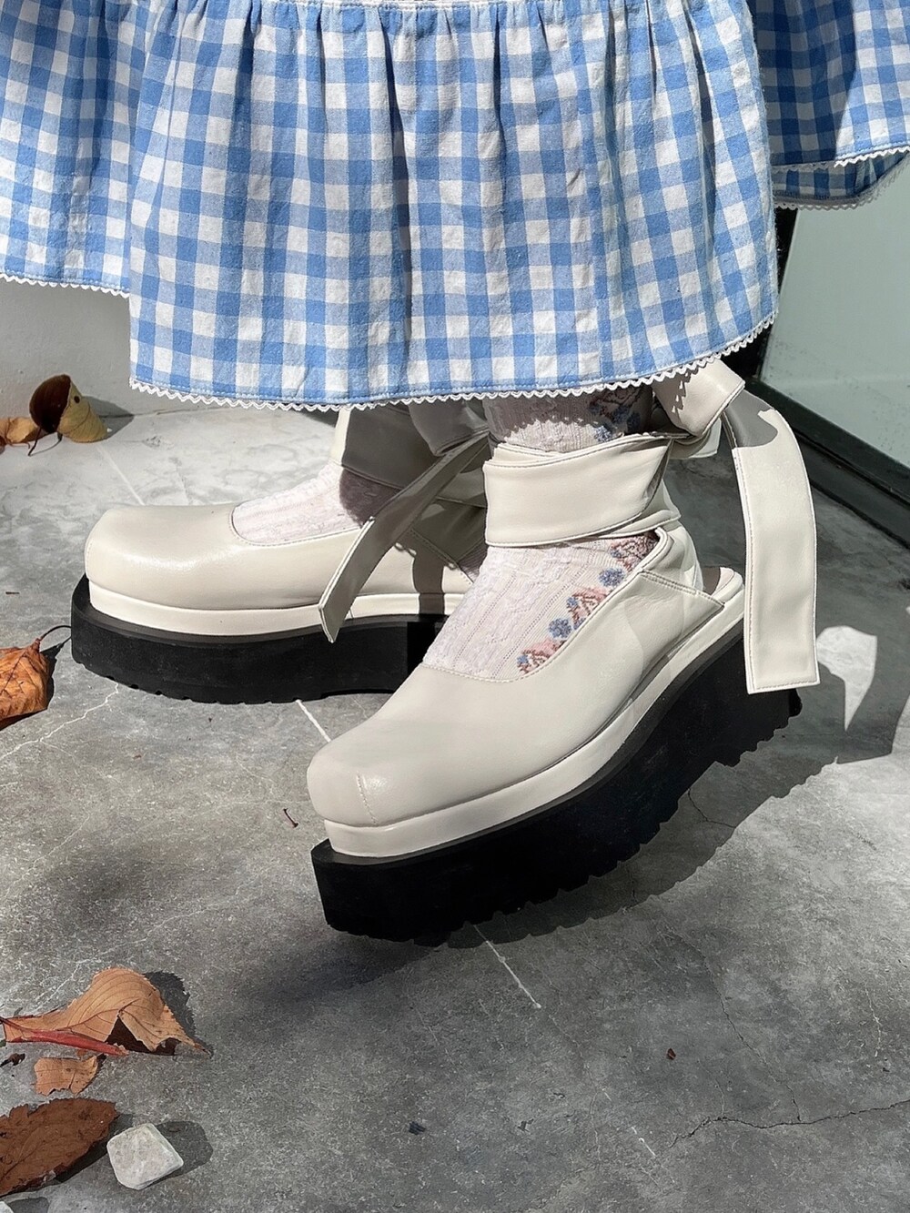 ホワイト系のニット/セーター、ブルー系のスカート、ホワイト系のパンプスを着用したレディースの秋コーディネートの5枚目の写真