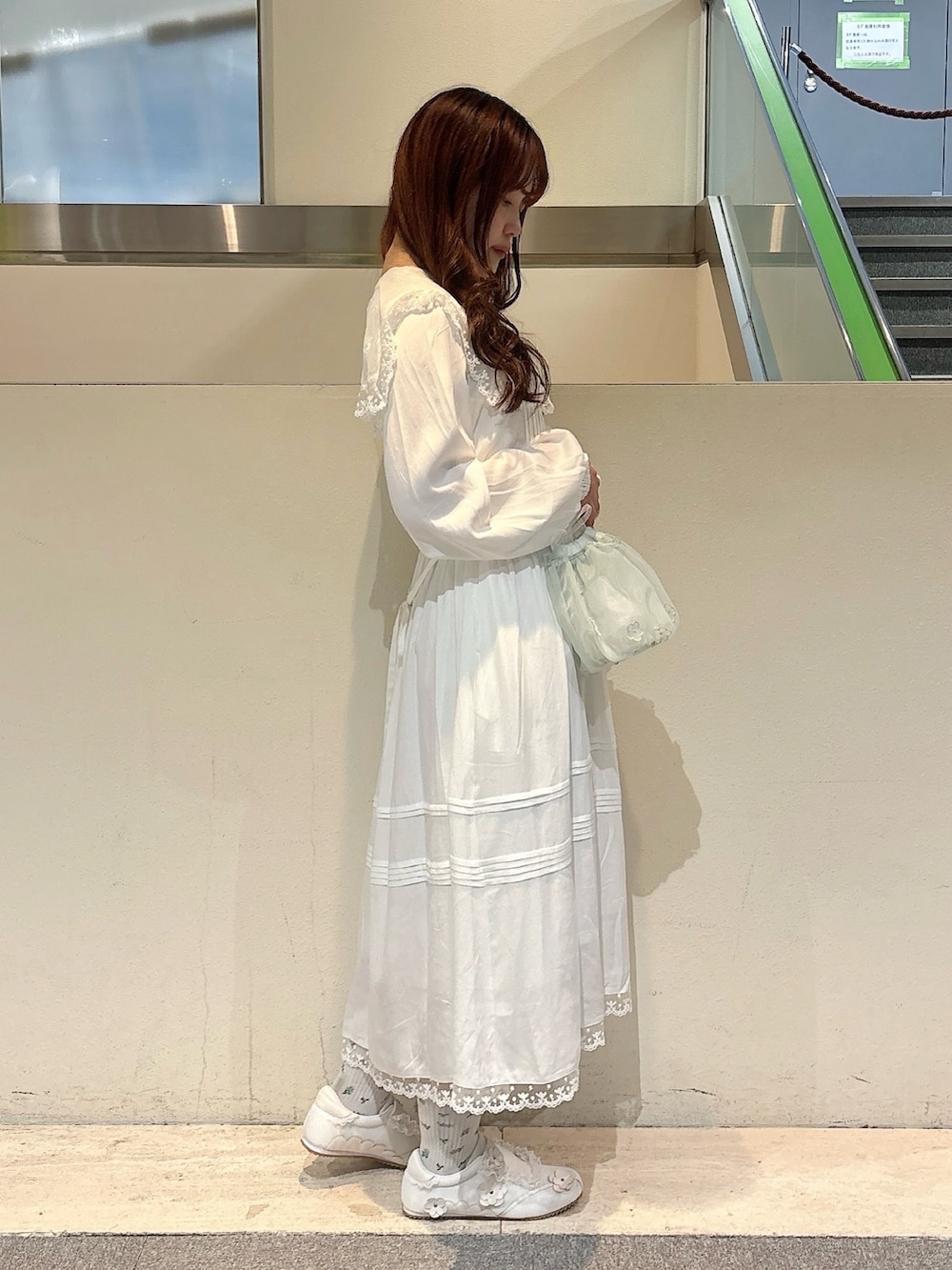 グリーン系のハンドバッグ、ホワイト系のスニーカー、ホワイト系のワンピースを着用したレディースの冬コーディネートの4枚目の写真