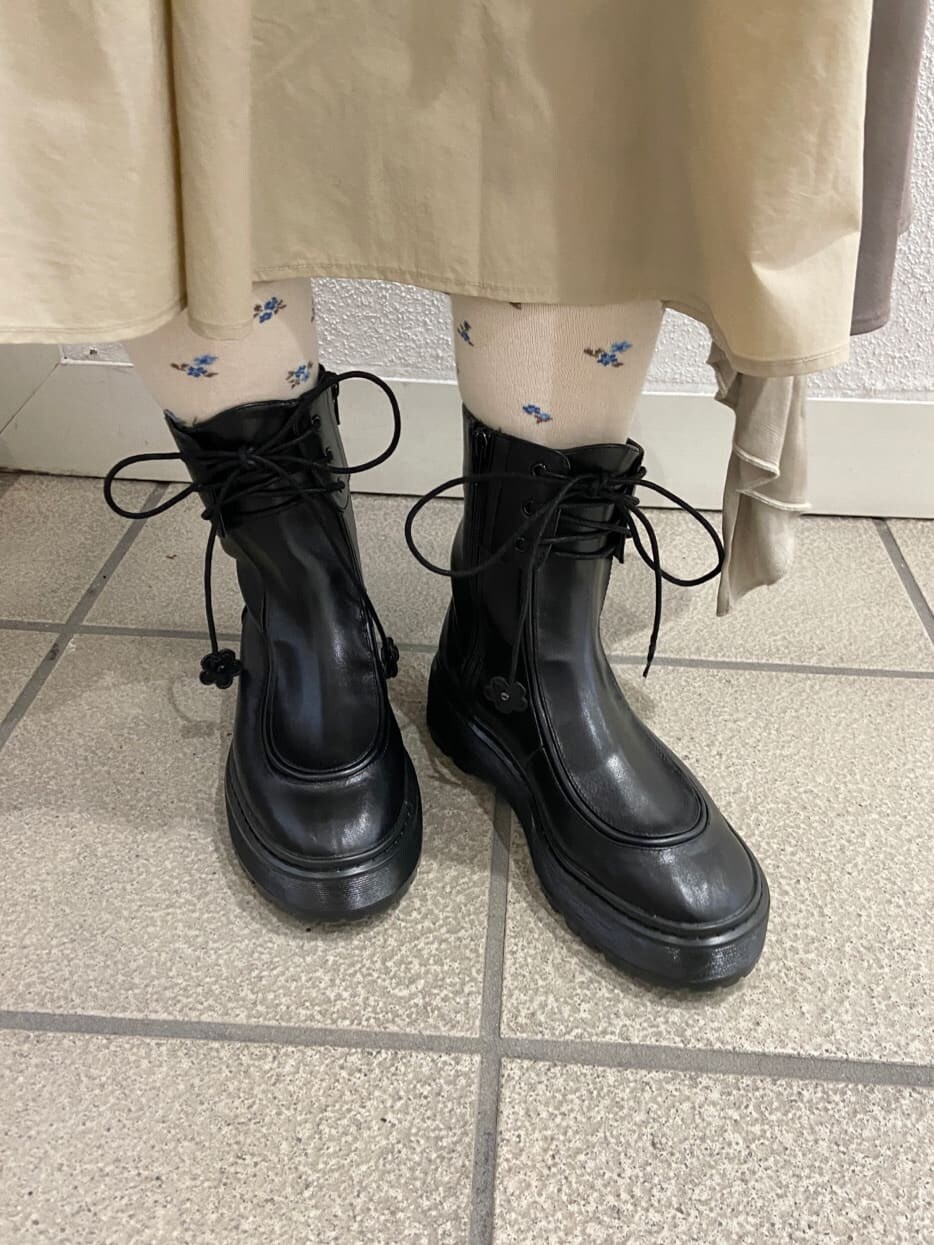 ブラック系のハンドバッグ、ブラック系のブーツ、ベージュ系のスカートを着用したレディースの冬コーディネートの10枚目の写真