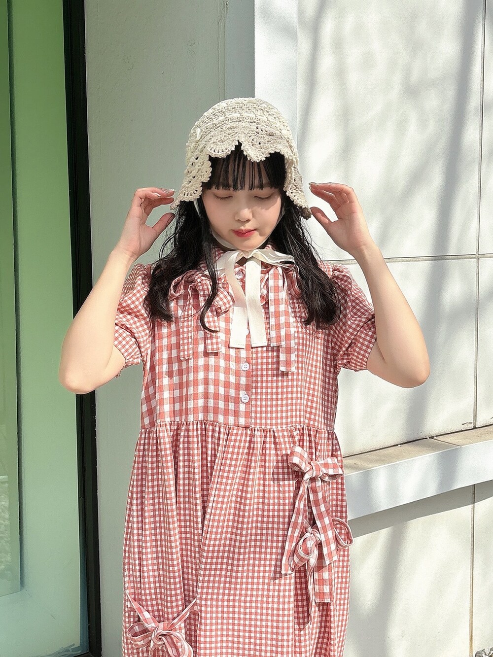 レッド系のワンピース、ホワイト系のスニーカー、ホワイト系のハットを着用したレディースの春コーディネートの6枚目の写真