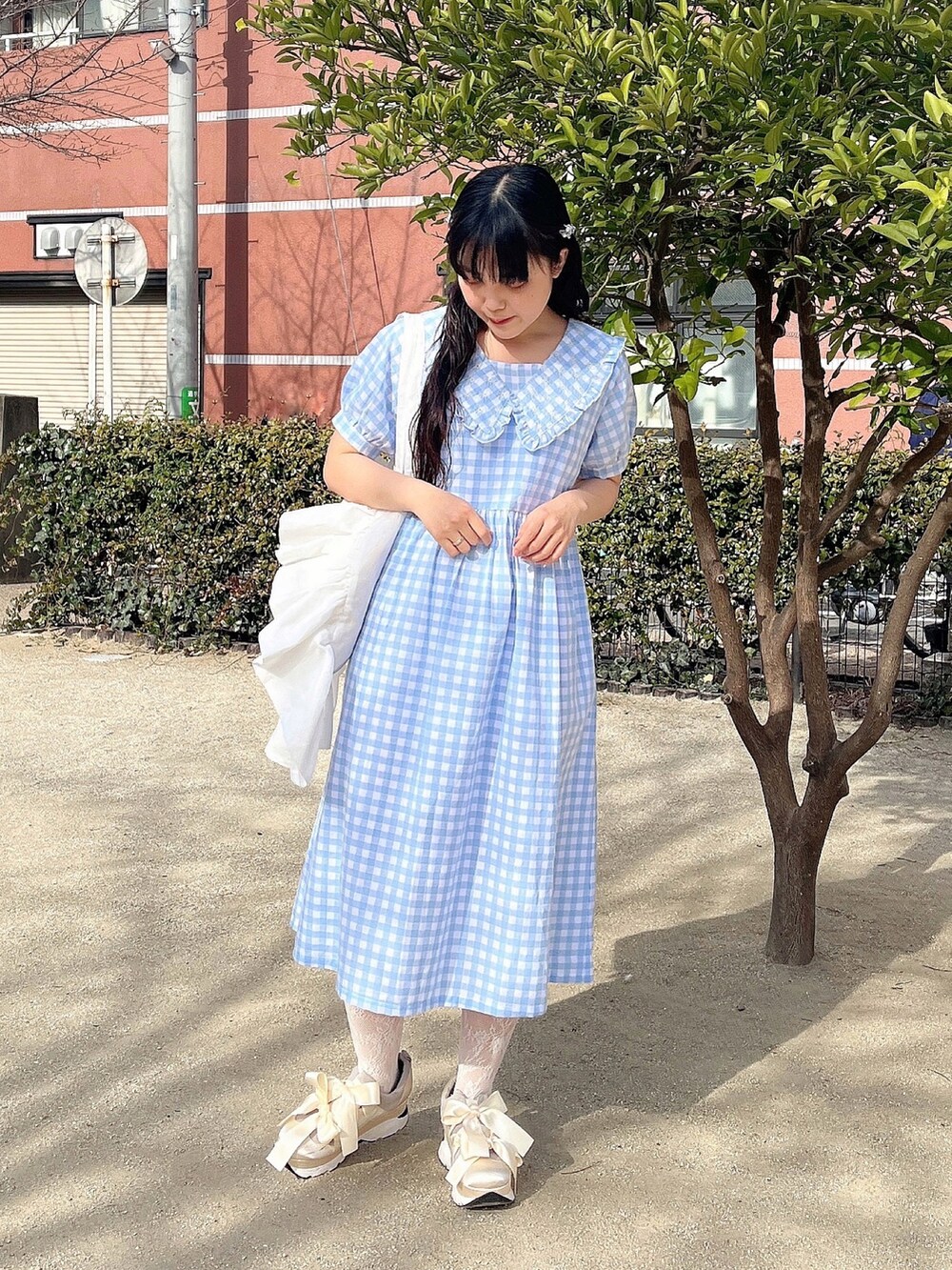 ホワイト系のトートバッグ、ブルー系のワンピース、ホワイト系のスニーカーを着用したレディースの冬コーディネートの2枚目の写真