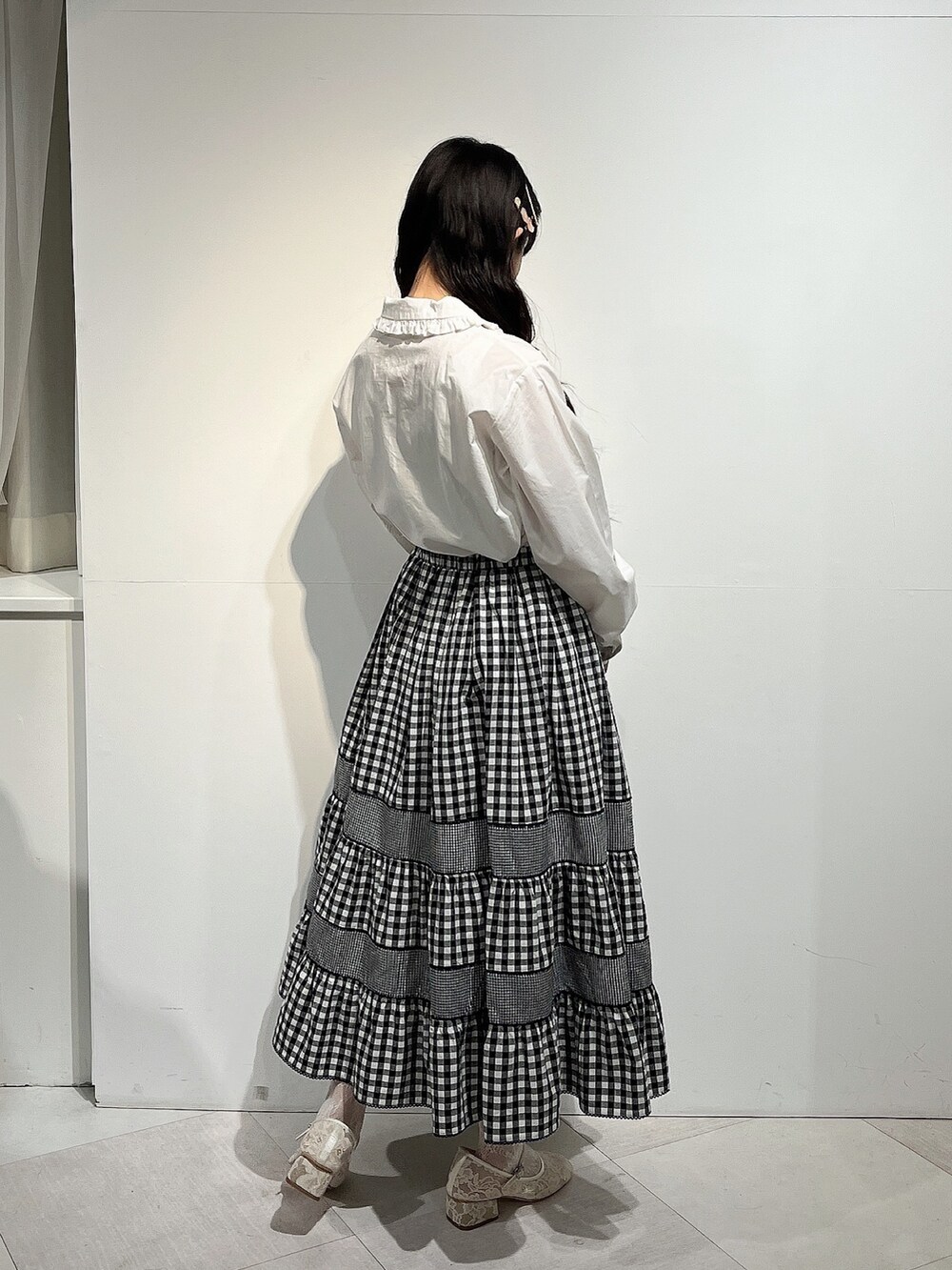 ホワイト系のシャツ/ブラウス、ブラック系のスカート、ホワイト系のパンプスを着用したレディースの春コーディネートの3枚目の写真