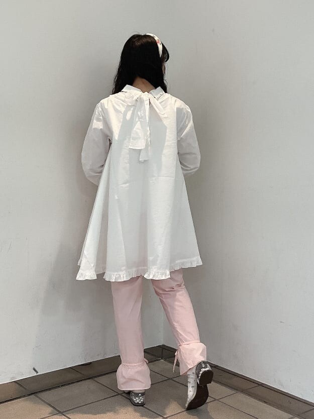 ピンク系のスラックス、ホワイト系のワンピース、ベージュ系のサンダルを着用したレディースの夏コーディネートの3枚目の写真