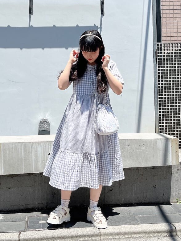 ホワイト系のサンダル、パープル系のハンドバッグ、パープル系のワンピースを着用したレディースの夏コーディネートの2枚目の写真