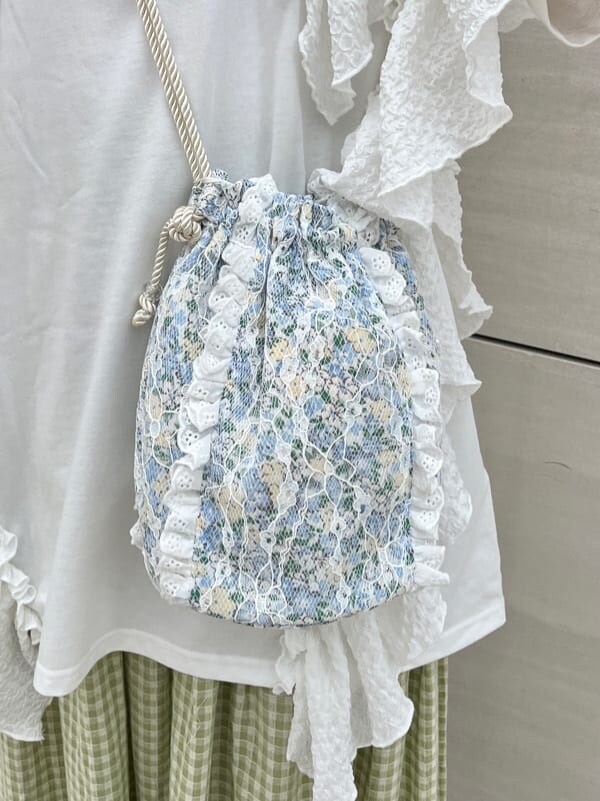 ホワイト系のチュニック、グリーン系のスカート、ホワイト系のサンダルを着用したレディースの春コーディネートの3枚目の写真