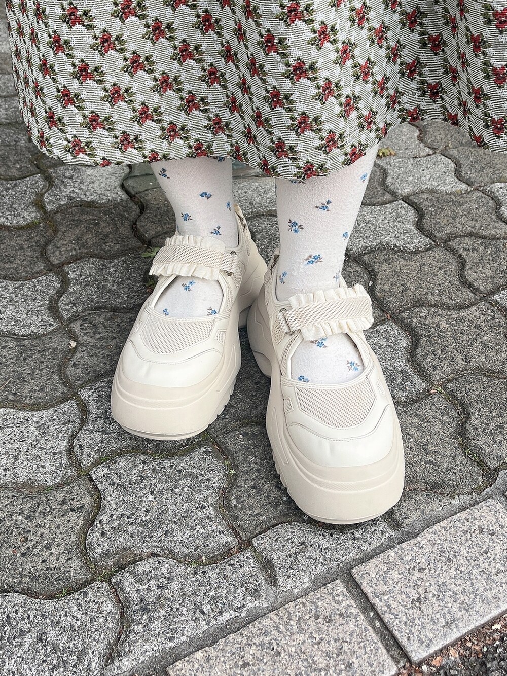 ホワイト系のニット/セーター、ホワイト系のダウンジャケット/コート、グリーン系のジャンパースカートを着用したレディースの冬コーディネートの8枚目の写真