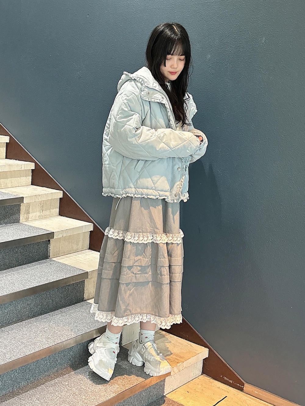 ブルー系のダウンジャケット/コート、ホワイト系のニット/セーター、グレー系のスカートを着用したレディースの秋コーディネートの3枚目の写真