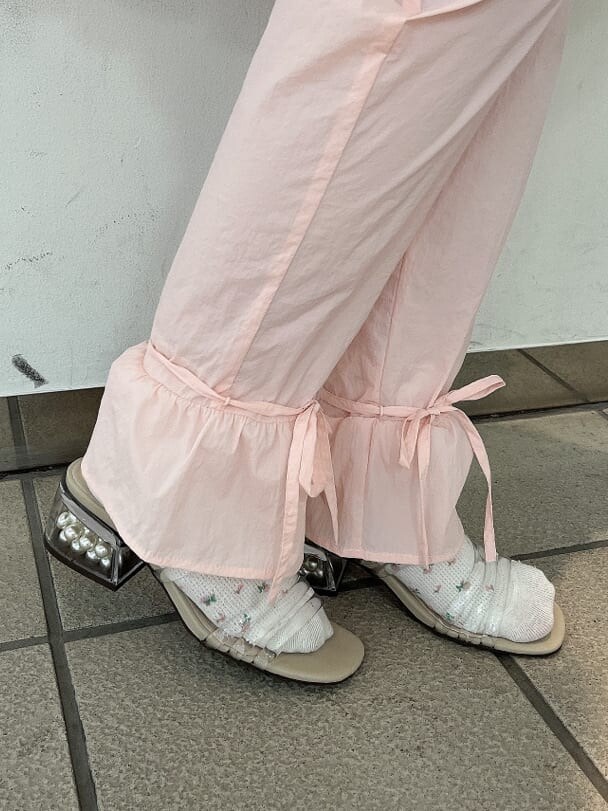 ピンク系のスラックス、ホワイト系のワンピース、ベージュ系のサンダルを着用したレディースの夏コーディネートの6枚目の写真