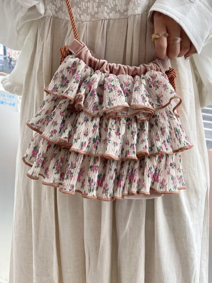 ホワイト系のテーラードジャケット、オレンジ系のハンドバッグ、ホワイト系のワンピースを着用したレディースの夏コーディネートの7枚目の写真