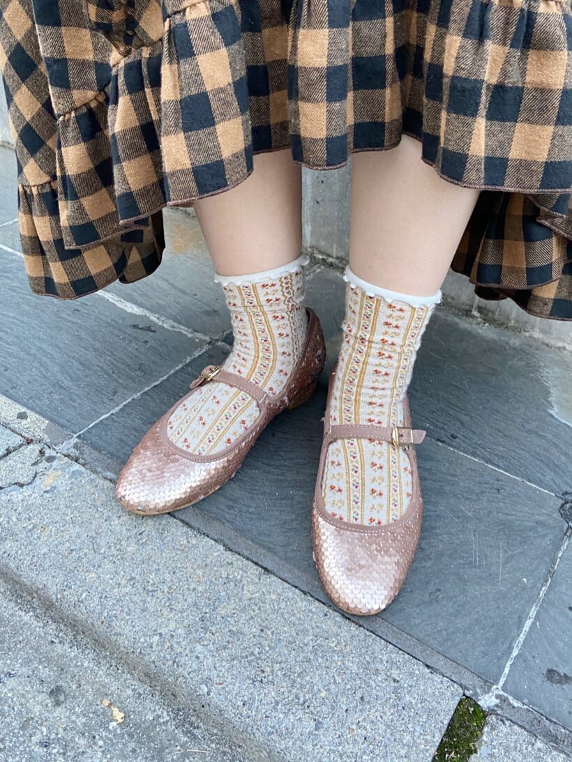 オレンジ系のスカート、ベージュ系のパンプス、ホワイト系のトートバッグを着用したレディースの秋コーディネートの7枚目の写真