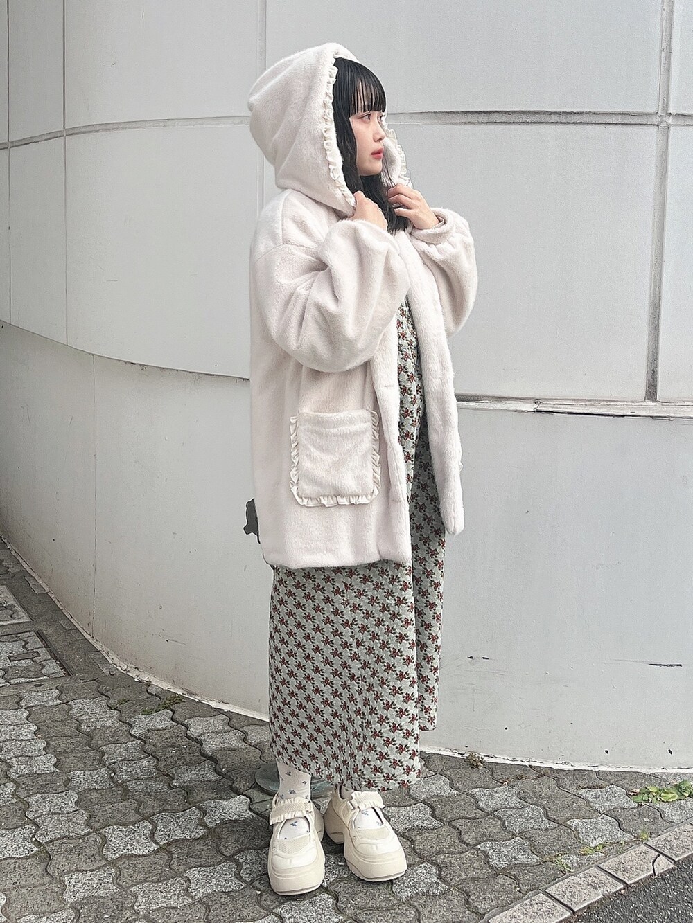 ホワイト系のニット/セーター、ホワイト系のダウンジャケット/コート、グリーン系のジャンパースカートを着用したレディースの冬コーディネートの3枚目の写真