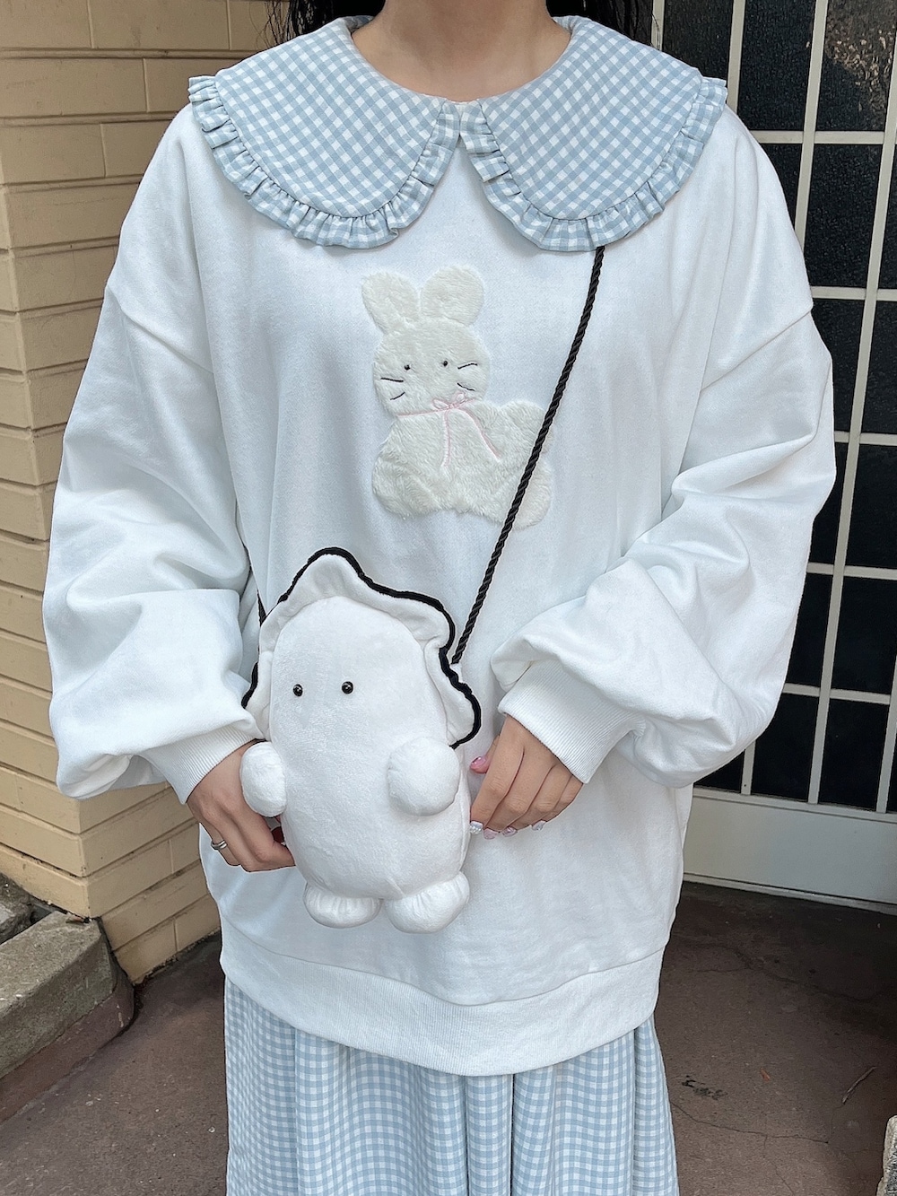 ホワイト系のスウェット、ホワイト系のショルダーバッグ、ブルー系のワンピースを着用したレディースの冬コーディネートの7枚目の写真