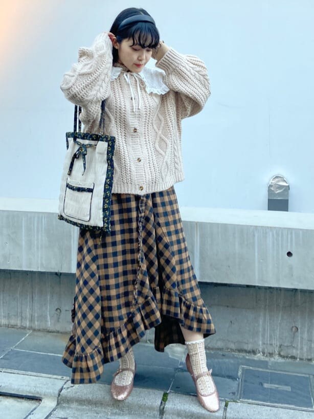 オレンジ系のスカート、ベージュ系のパンプス、ホワイト系のトートバッグを着用したレディースの秋コーディネートの2枚目の写真