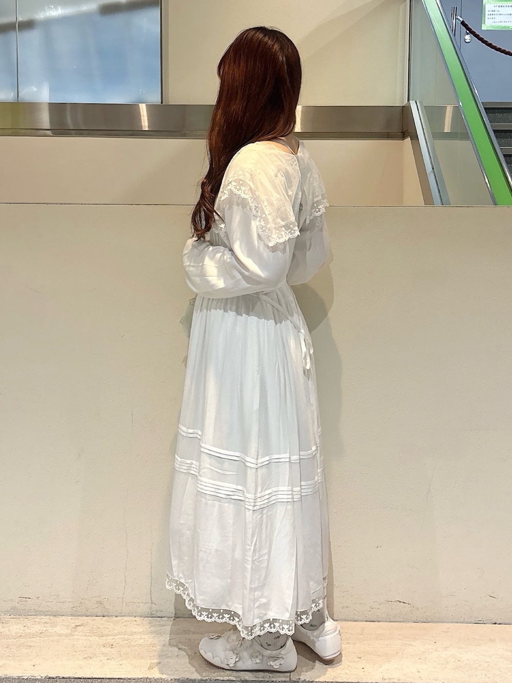 グリーン系のハンドバッグ、ホワイト系のスニーカー、ホワイト系のワンピースを着用したレディースの冬コーディネートの5枚目の写真