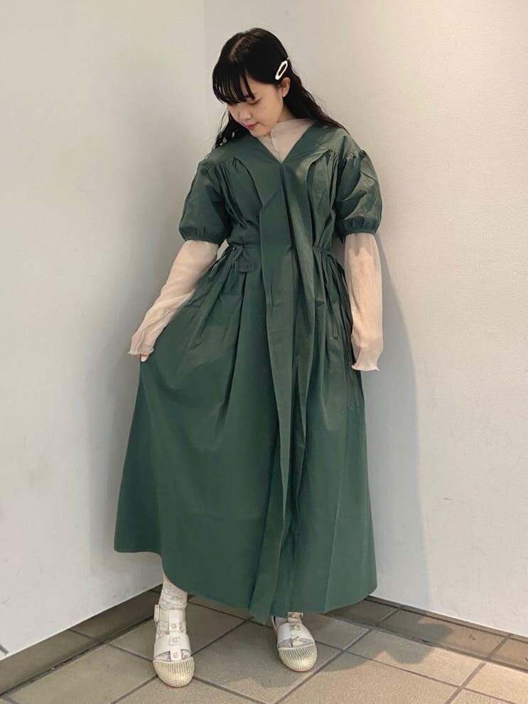 ベージュ系のパンプス、グリーン系のワンピース、ホワイト系のチュニックを着用したレディースの夏コーディネートの2枚目の写真