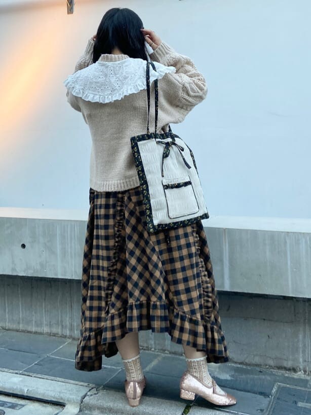 オレンジ系のスカート、ベージュ系のパンプス、ホワイト系のトートバッグを着用したレディースの秋コーディネートの3枚目の写真