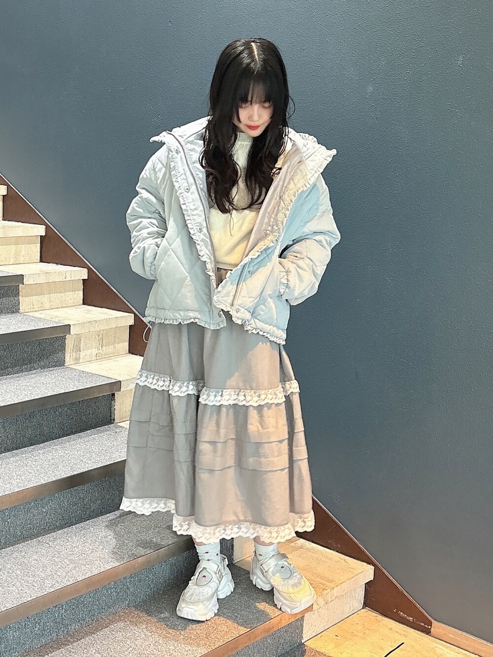 ブルー系のダウンジャケット/コート、ホワイト系のニット/セーター、グレー系のスカートを着用したレディースの秋コーディネートの2枚目の写真