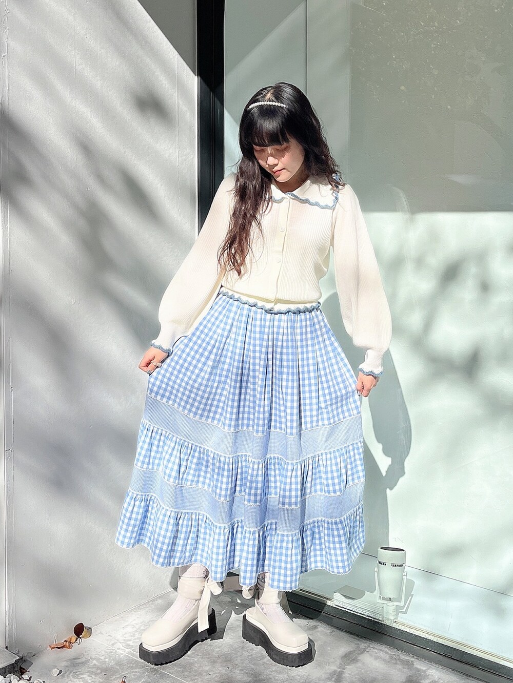 ホワイト系のニット/セーター、ブルー系のスカート、ホワイト系のパンプスを着用したレディースの秋コーディネートの2枚目の写真